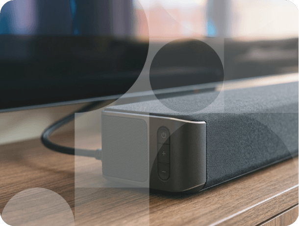 Close-up of wired soundbar on wooden TV stand with control buttons visible