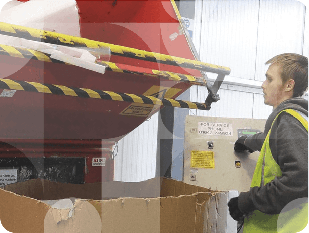 Worker operating industrial recycling machine to process old appliance materials in warehouse